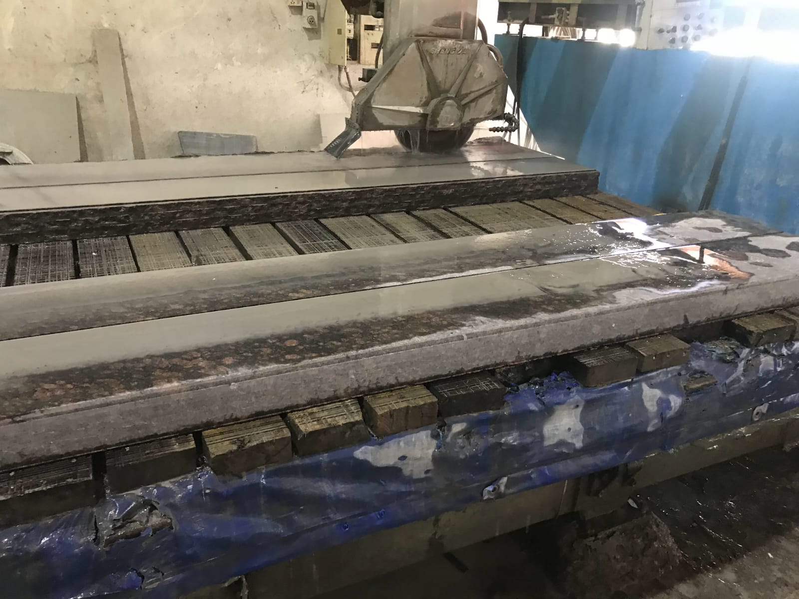 Bridge saw cutting a granite slab with water cooling on the factory line